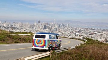 VW transporter from San Francisco Love Tours coming down Twin Peaks with city in the background