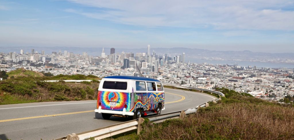 VW transporter from San Francisco Love Tours coming down Twin Peaks with city in the background